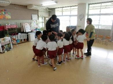 園児が英語の先生を囲んで英語を教わっている様子の写真