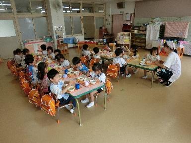 給食室で園児たちが給食を食べている様子の写真