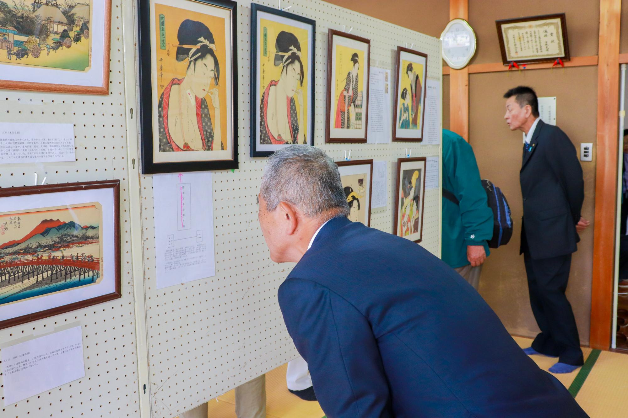 下牧地区で開催された浮世絵等展覧会で、作品の説明文を読む町長の様子