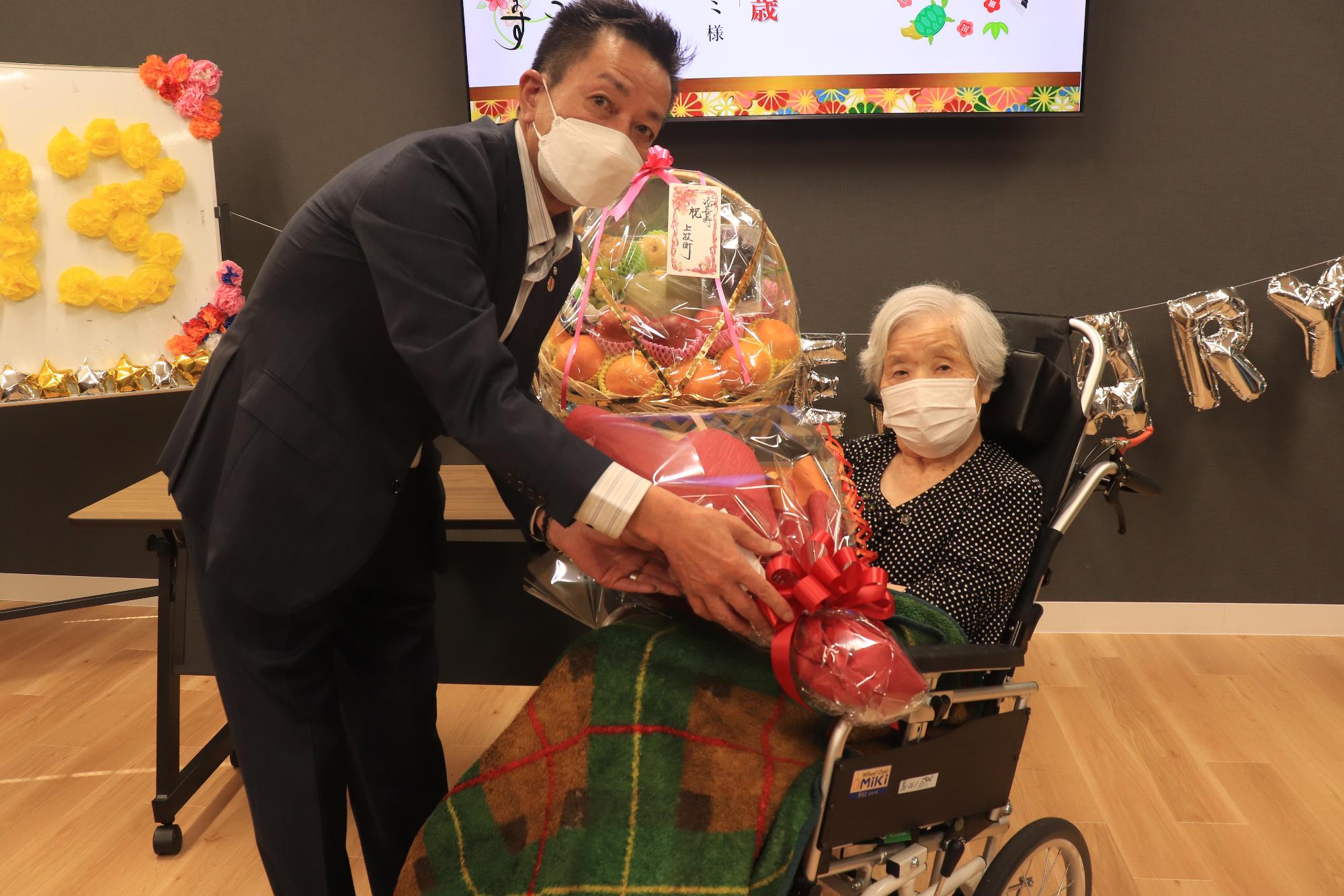 町内施設最高齢者のかたへ花束を渡す阪本町長