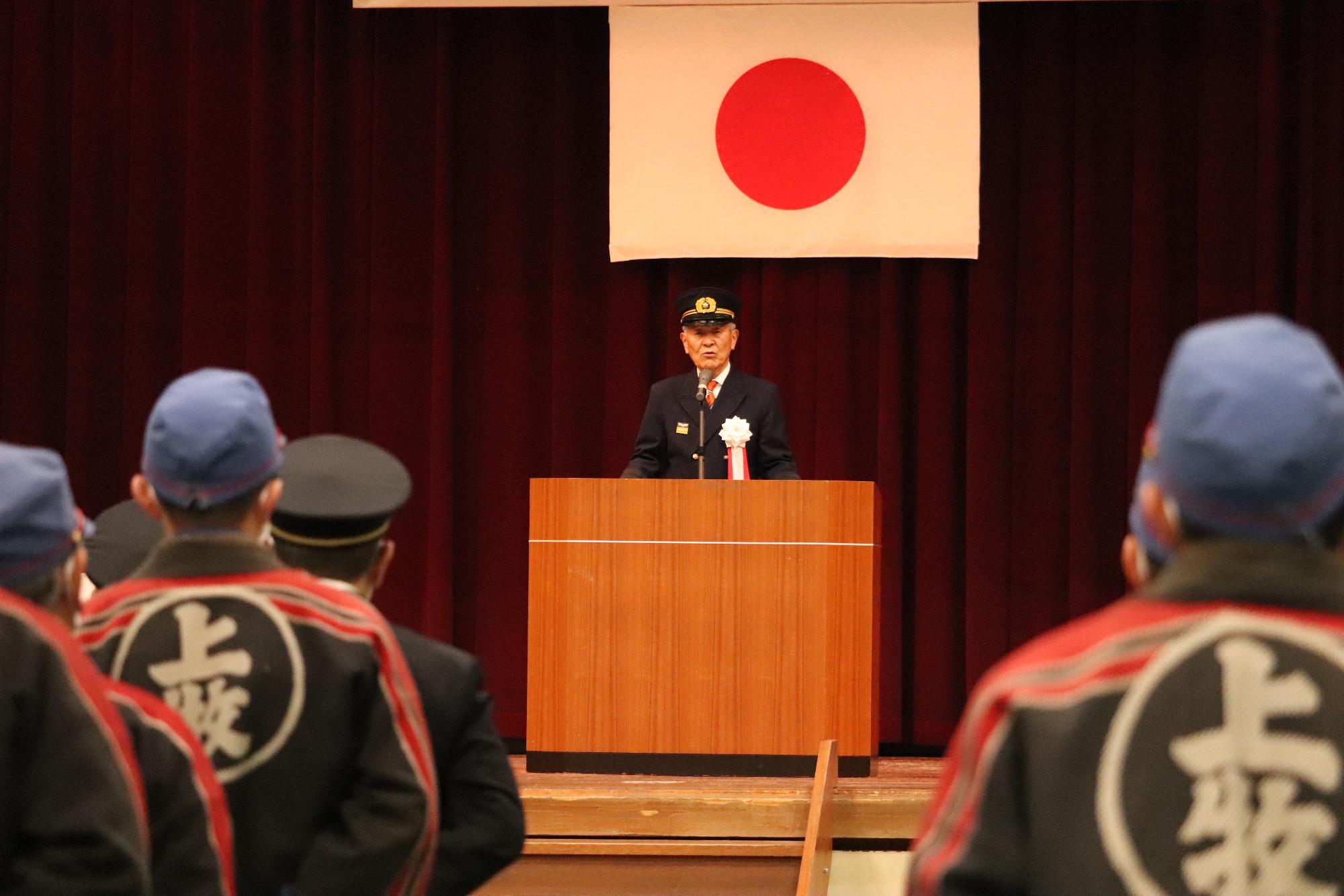 上牧町消防団の団員に舞台にのぼった今中町長が激励の言葉を贈る様子