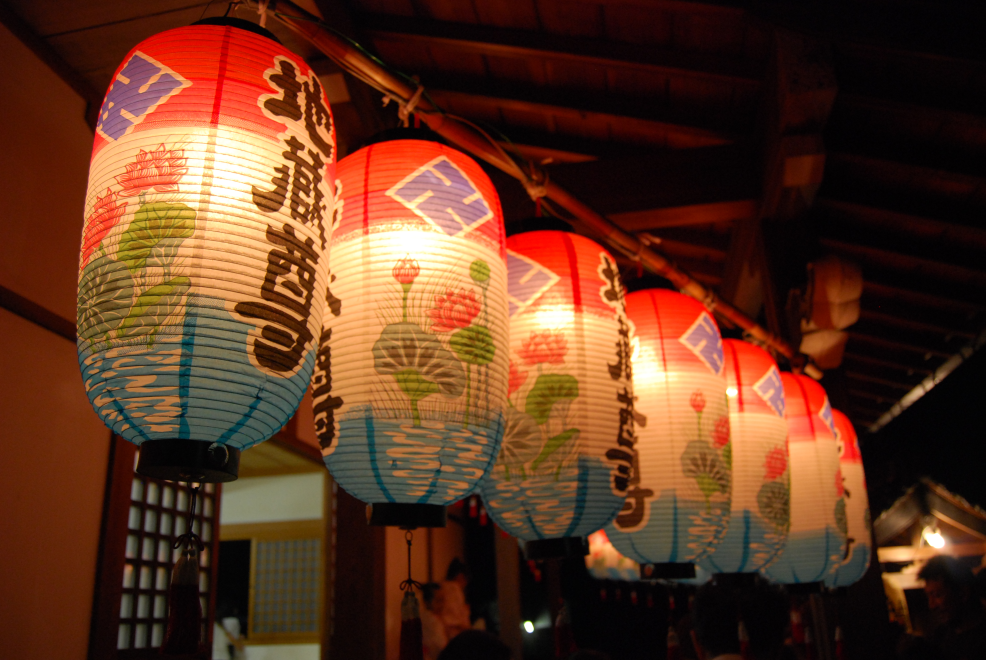神社に地蔵盆の提灯が6つほど吊るされている風景写真