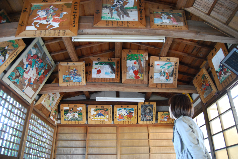 智照神社の天井に飾られた絵を眺める女性